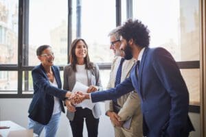 Man and woman dressed in business attire shaking hands while smiling