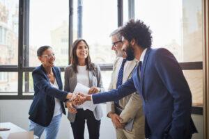 Man and woman dressed in business attire shaking hands while smiling