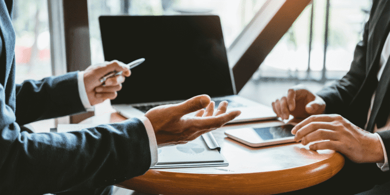 Two people sitting at a table discussing documents.|what to look for in a managed services provider|how do I choose a service provider?