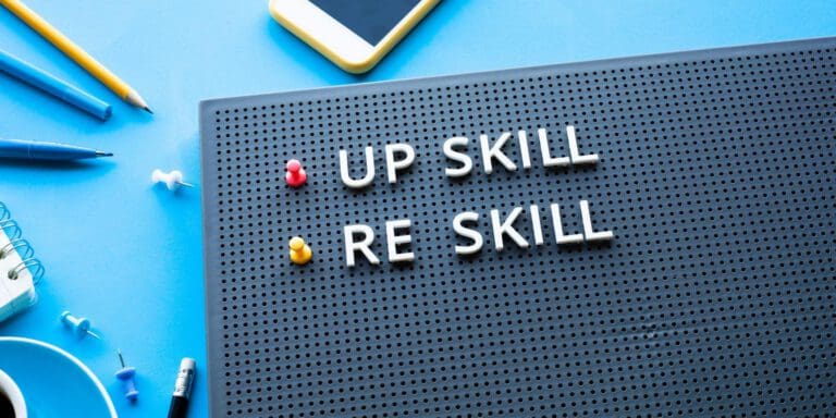 message board with "upskill" and "reskill" spelled out on int|man working on upskilling on his computer