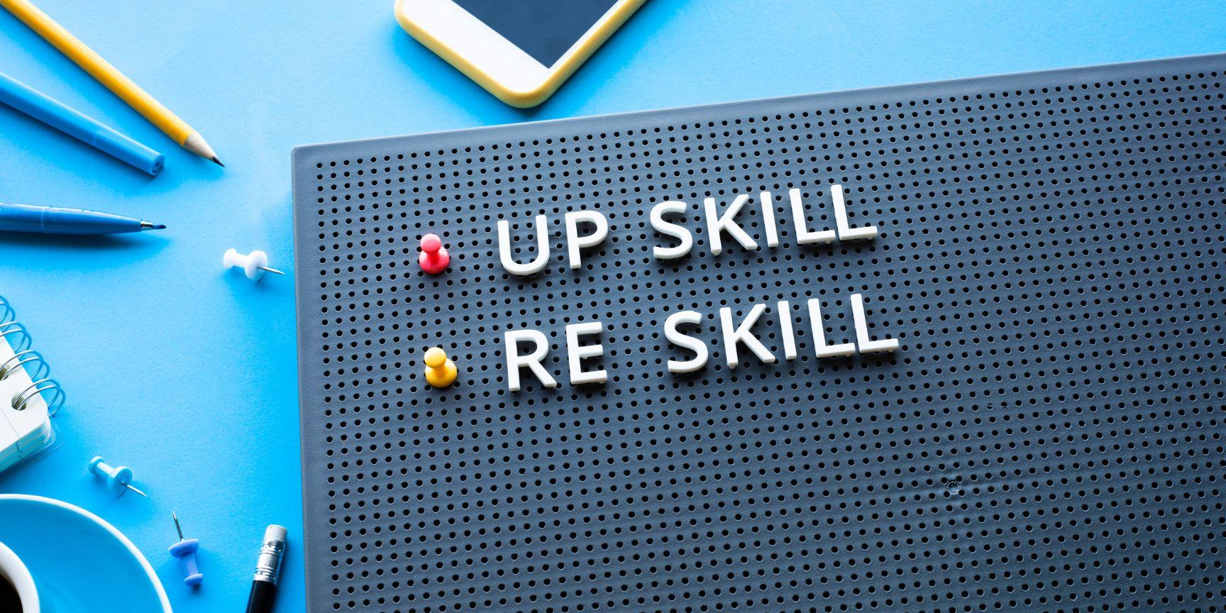 message board with "upskill" and "reskill" spelled out on int|man working on upskilling on his computer