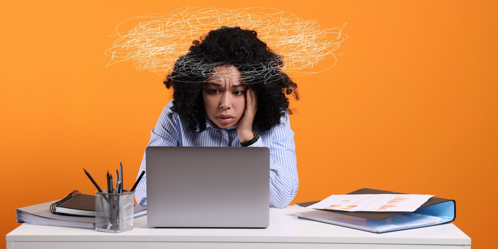 worried woman looking at laptop at desk with doodles around her head