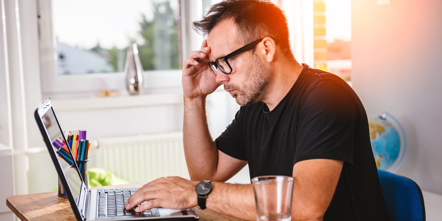 man working on his laptop at a table in his home